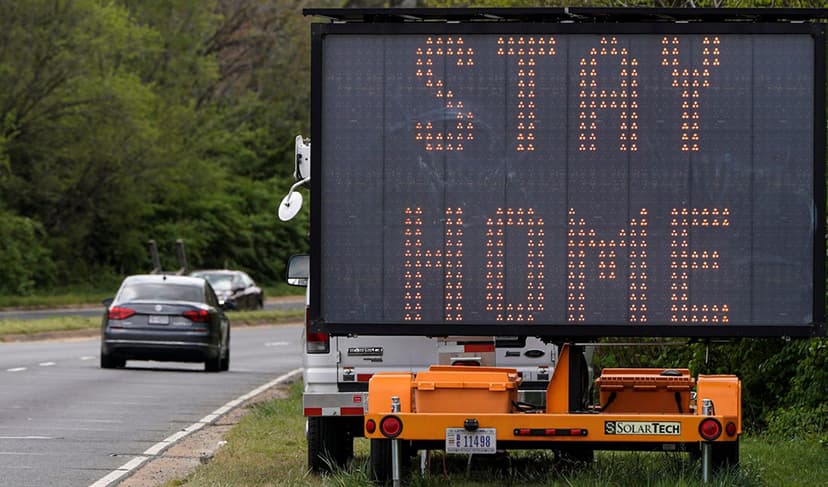 Car alongside Stay Home signage