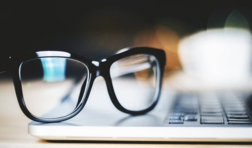 Pair of glasses beside a laptop