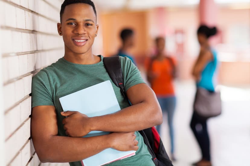 Young man leaning against wall in college