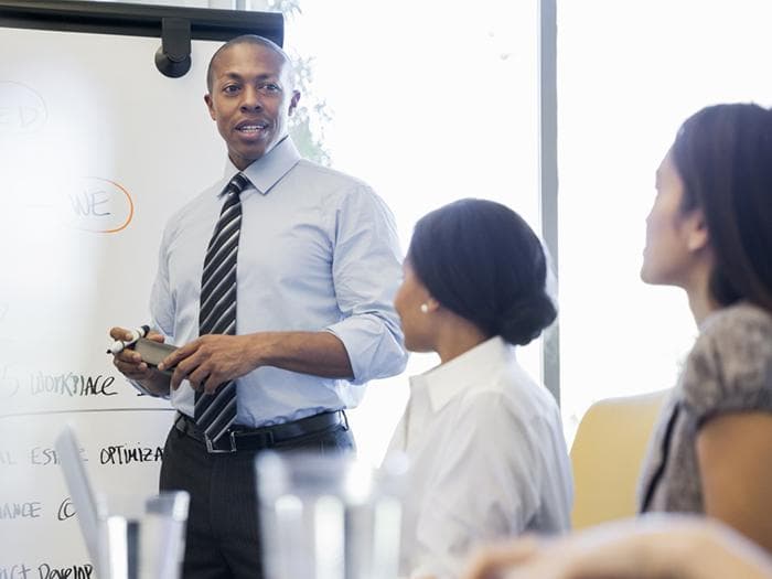 Two women watching a man's presentation