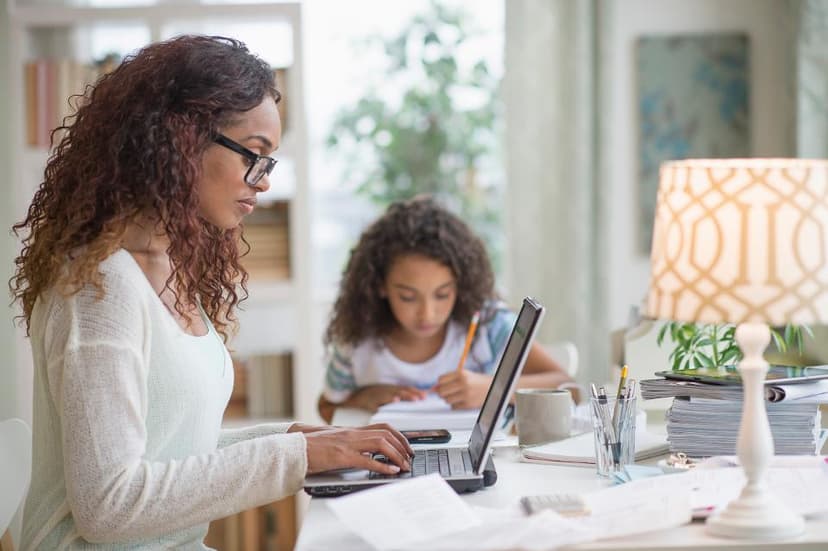 woman working on laptop alongside daughter