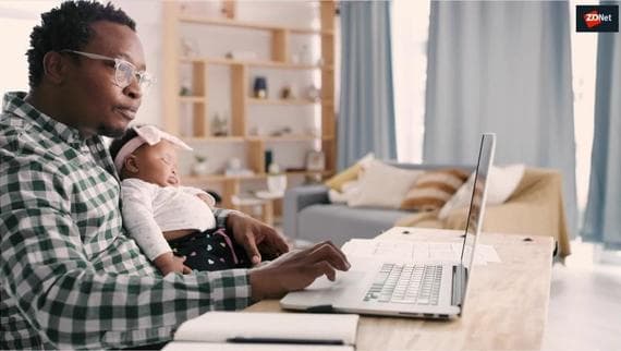 Man holding baby and working on a laptop