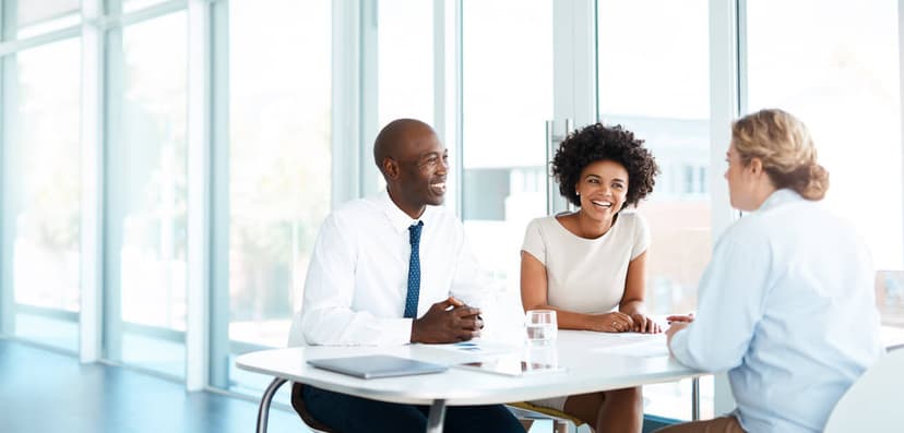 couple seated at a table talking to a woman