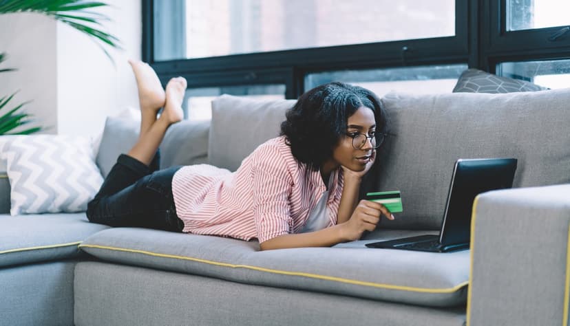 Woman laying on a couch with a credit card