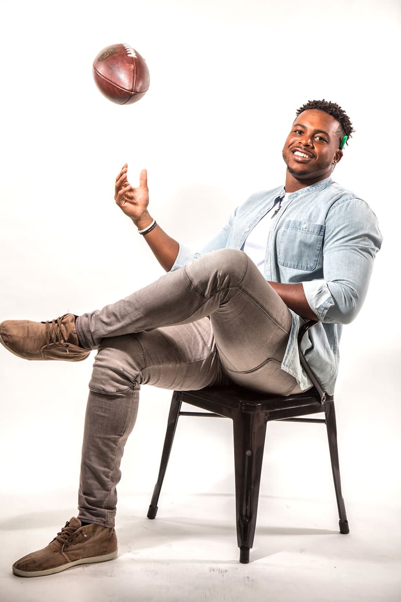 Man seated on chair tossing a football in the air