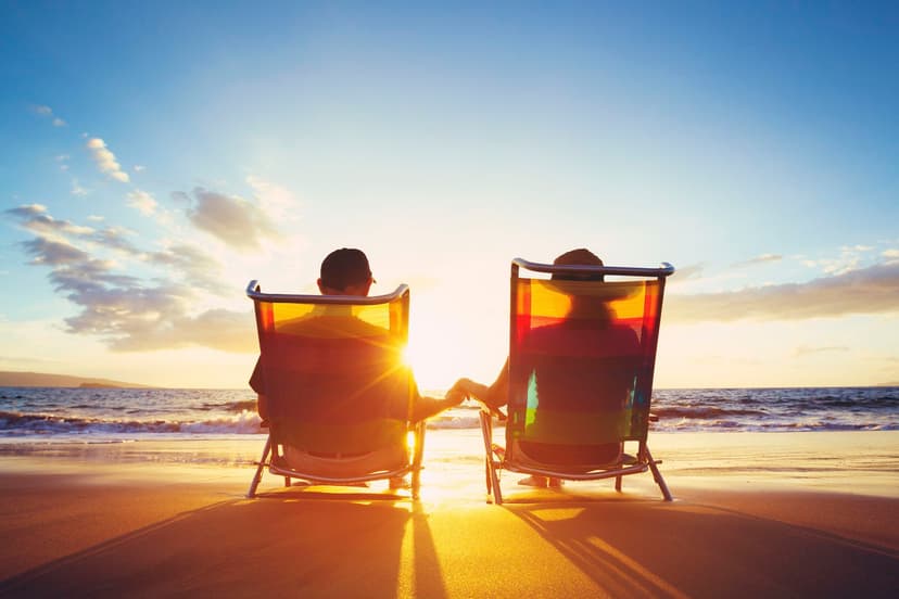 Two people seated in beach chairs on the sand