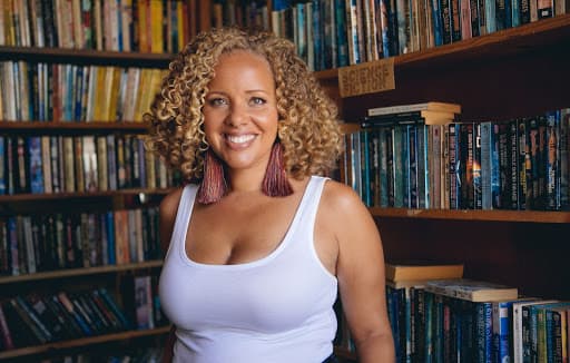 Woman in white top standing in front of books