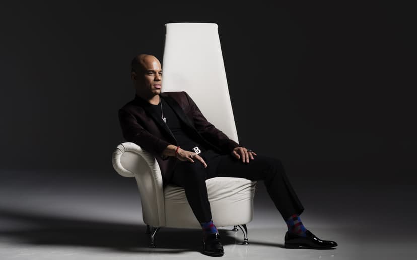 Man seated in Black suit in white chair